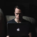 Un homme seul devant un ordinateur dans la pénombre