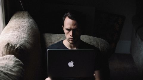 Un homme seul devant un ordinateur dans la pénombre