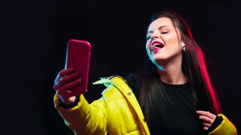 une fille regarde son portable en tirant la langue