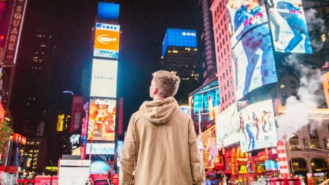 Adolescent de dos à Time Square, devant les affichages publicitaires lumineux