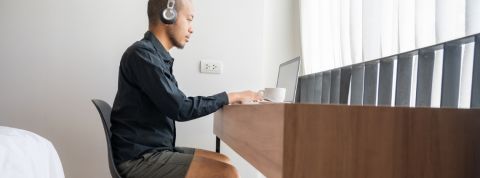 On peut désormais travailler... en vacances Un homme dans sa chambre d'hôtel en train de télétravailler