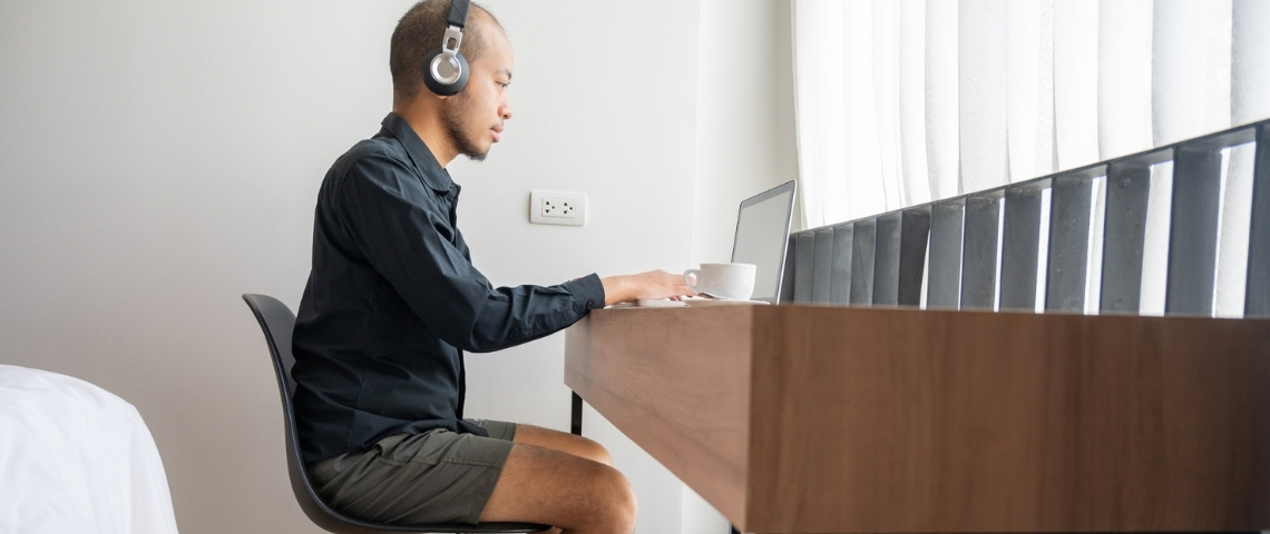 On peut désormais travailler... en vacances Un homme dans sa chambre d'hôtel en train de télétravailler