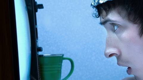 un homme regarde la télévision de très près