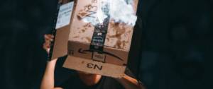 Un homme tient un carton Amazon en train de brûler