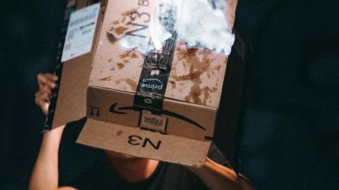 Un homme tient un carton Amazon en train de brûler