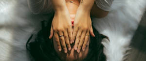 Une femme allongée sur son lit, se tenant le visage dans ses mains