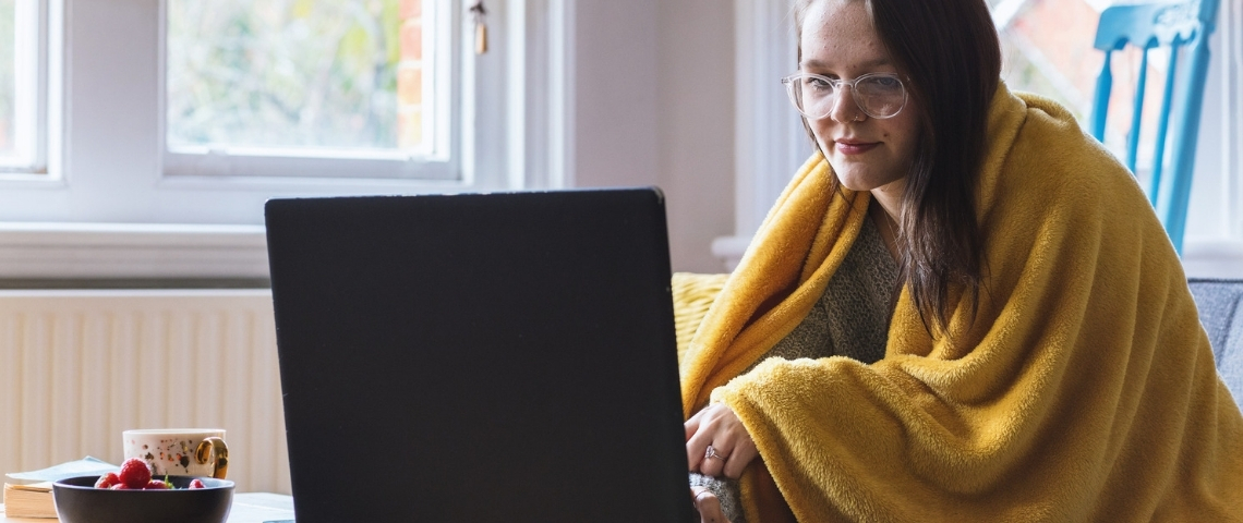 Que s'est-il passé pendant notre première semaine de reconfinement ? Une jeune femme, un plaid enroulé autour de ses épaules, sur son ordinateur