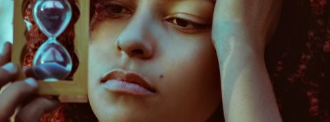 Quelles sont les actualités de notre troisième semaine de confinement ? Une jeune femme s'ennuyant, tenant un sablier