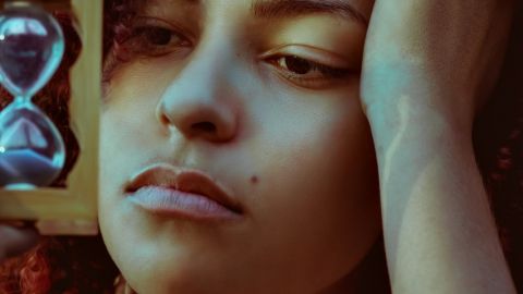 Une jeune femme s'ennuyant, tenant un sablier