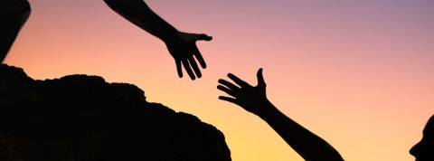 Comment le e-commerce soutient les petits commerçants ? Une personne en train d'aider une autre personne à gravir un rocher