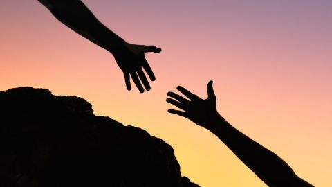 Comment le e-commerce soutient les petits commerçants ?  Une personne en train d'aider une autre personne à gravir un rocher