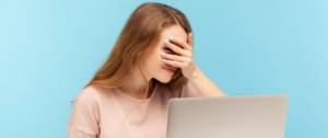 Une femme devant son écran d'ordinateur se cache le visage