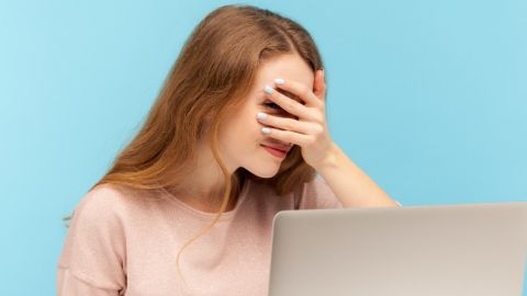 Une femme devant son écran d'ordinateur se cache le visage