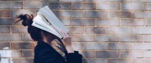 Une femme se cache le visage avec un livre