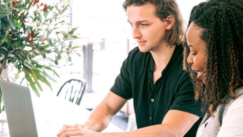 Une jeune femme noire et un jeune homme blanc en train de travailler