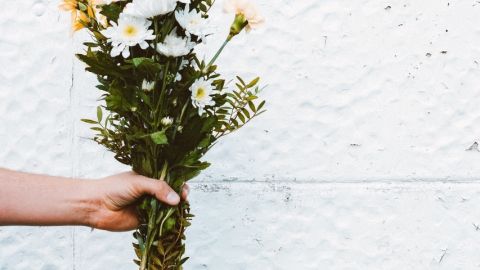 Quelles sont les bonnes nouvelles du confinement ?  Une main tenant un bouquet de fleurs blanches