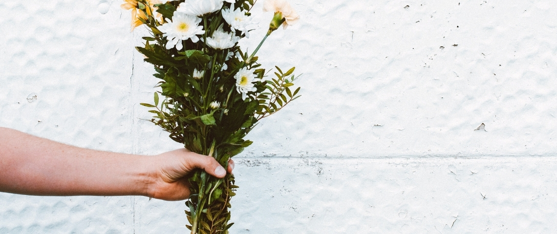 Quelles sont les bonnes nouvelles du confinement ? Une main tenant un bouquet de fleurs blanches