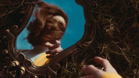 Une femme qui se regarde dans un miroir posé par terre