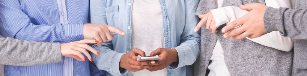 Des personnes en train de pointer le smartphone d'une personne au centre d'un groupe