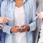 Des personnes en train de pointer le smartphone d'une personne au centre d'un groupe