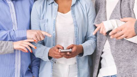 Des personnes en train de pointer le smartphone d'une personne au centre d'un groupe