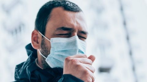 Monsieur portant un masque en train de tousser en extérieur
