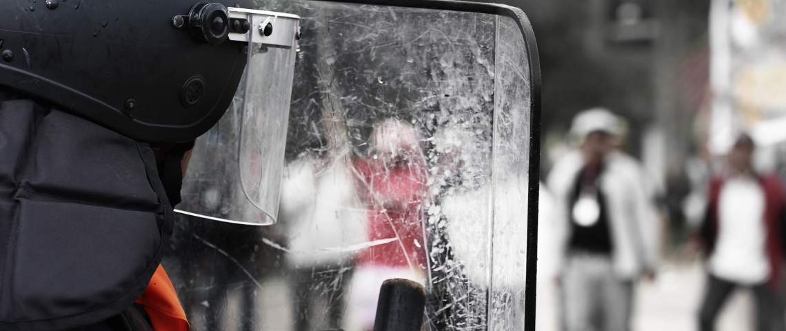 Un projet de loi liberticide ? derrière le bouclier transparent d'un policier.