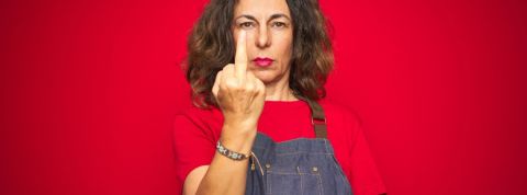 Pourquoi certains restaurants boycottent Deliveroo pendant le reconfinement ? Une femme cheffe cuisinière en train de faire un doigt d'honneur