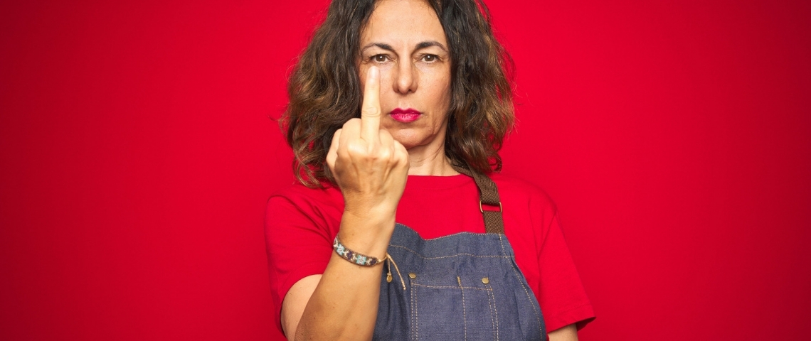 Pourquoi certains restaurants boycottent Deliveroo pendant le reconfinement ? Une femme cheffe cuisinière en train de faire un doigt d'honneur