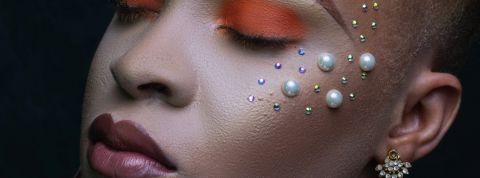 Quel a été l'impact de 2020 sur la beauté ? Une femme métisse, les yeux fermés, les paupières fardées d'orange et des perles posées sur les joues