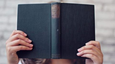 Une femme cachée derrière un livre