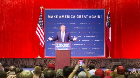 un meeting de Trump avec un fond rouge