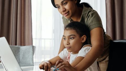 Une mère qui aide sa fille à faire ses devoirs devant l'ordinateur