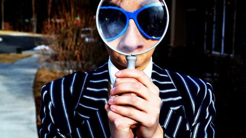 Un homme tenant une loupe devant ses yeux