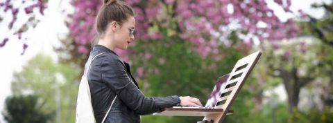 Travail a distance et nomadisme, le futur du travail Dehors dans un parc, une jeune femme travaille sur son ordinateur