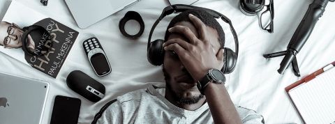 Génération Z en entreprise : quelles sont leurs attentes ? Un jeune homme noir allongé sur son lit entouré d'objets