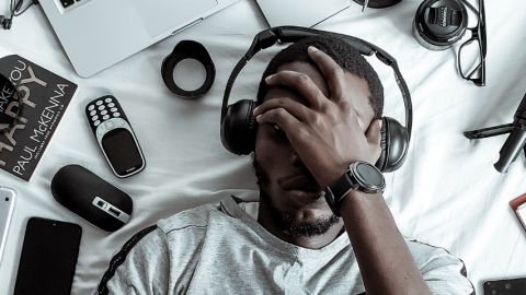 Un jeune homme noir allongé sur son lit entouré d'objets