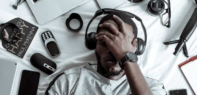 Un jeune homme noir allongé sur son lit entouré d'objets