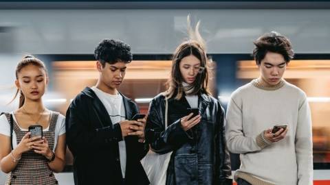 Quatre adolescents qui regardent leur téléphone portable
