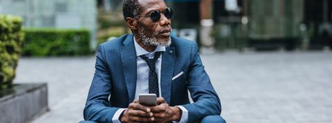 WhatsApp et business : que fabrique Facebook avec sa messagerie Un homme d'affaire noir consulte son smartphone