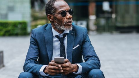 Un homme d'affaire noir consulte son smartphone