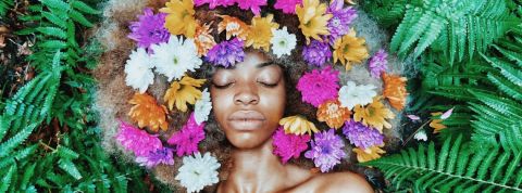 Quelles entreprises ont la meilleure réputation RSE ? Une femme noire posant sur des feuilles, les cheveux remplis de fleurs