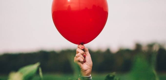 Une femme tient un ballon rouge, symbole de sa résilience