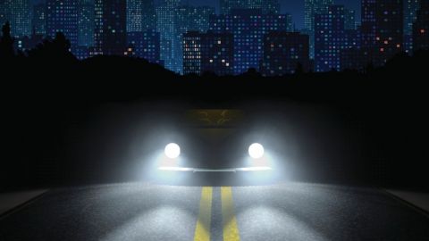 Une voiture avec les phares allumés dans la nuit