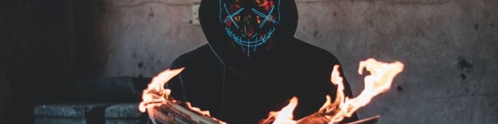 Un homme masqué en train de lire un journal en feu