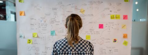 Balance ta start-up : le but n'est pas seulement de recueillir des témoignages mais de trouver des solutions Une femme devant un tableau recouvert de post-it et de notes