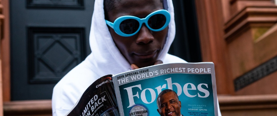 Forbes lance une plateforme de newsletters pour journalistes entrepreneurs Jeune homme en train de lire un numéro du magazine Forbes