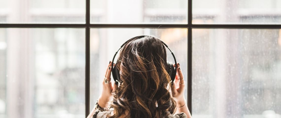 L'agence idenium rend audio ses communiqués avec ETX Daily Up Femme de dos avec un casque sur les oreilles