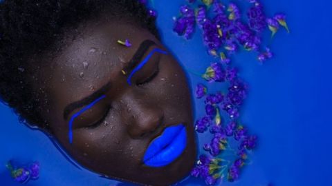Une femme avec des lèvres bleues dans une baignoire remplie de liquide bleu