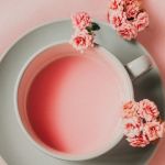Une tasse avec un liquide rose et des fleurs roses